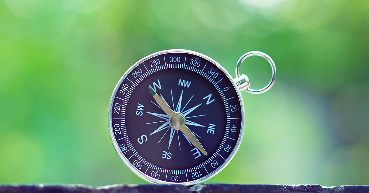 Compass with smooth blur green background, journey planning concept.