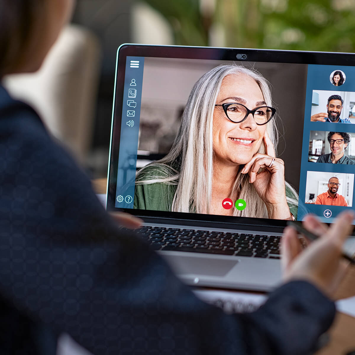 Rear view of business woman in video conference with boss and his colleagues during online meeting.